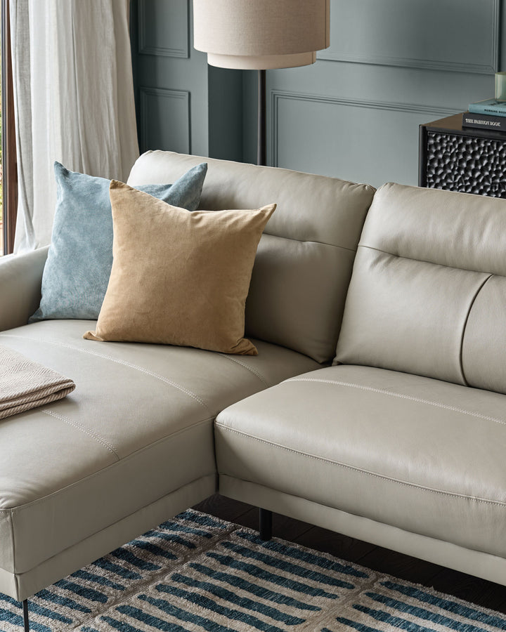 Brooks leather left-hand corner chaise sofa in light grey, styled with decorative pillows in a modern living room setting.