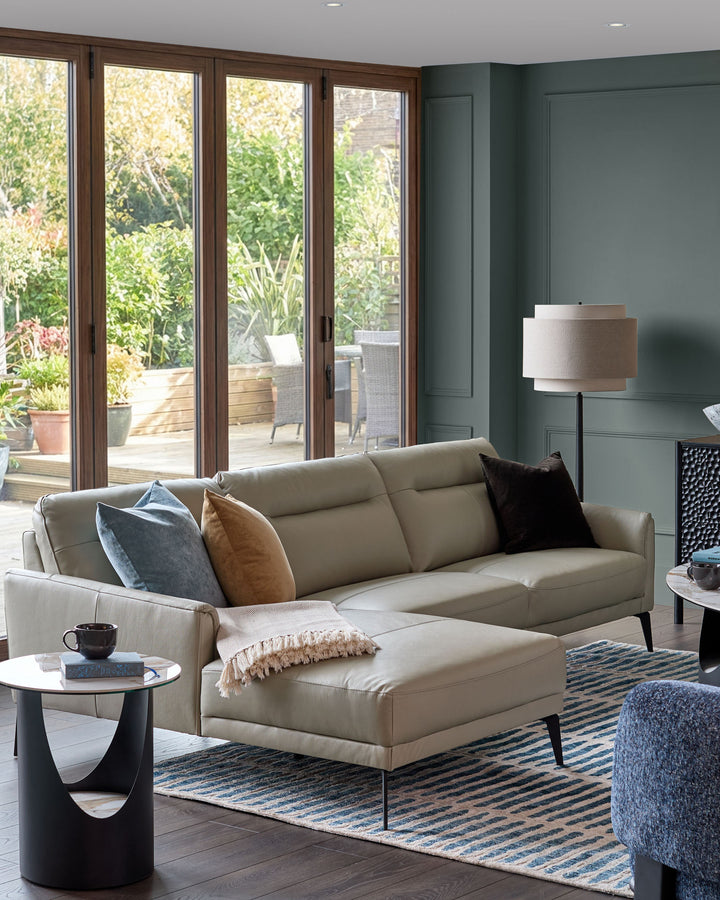 Brooks leather left-hand corner chaise sofa in light grey, styled in a modern living room with garden views.
