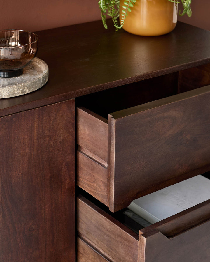 A dark wood sideboard with open drawers, showcasing the storage and design details.