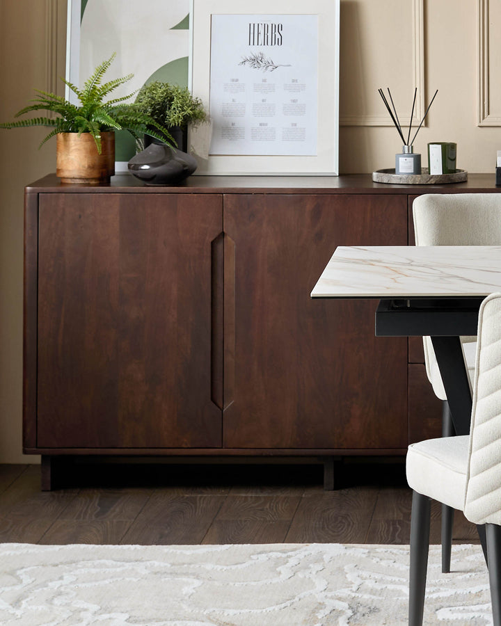A dark wood sideboard sits against a wall with framed prints. A marble table and cream chairs sit to the side.