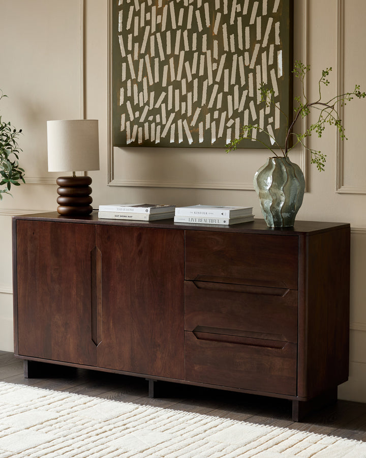 Dark mango wood sideboard with two cabinet doors and two drawers, displayed in a styled living room setting.