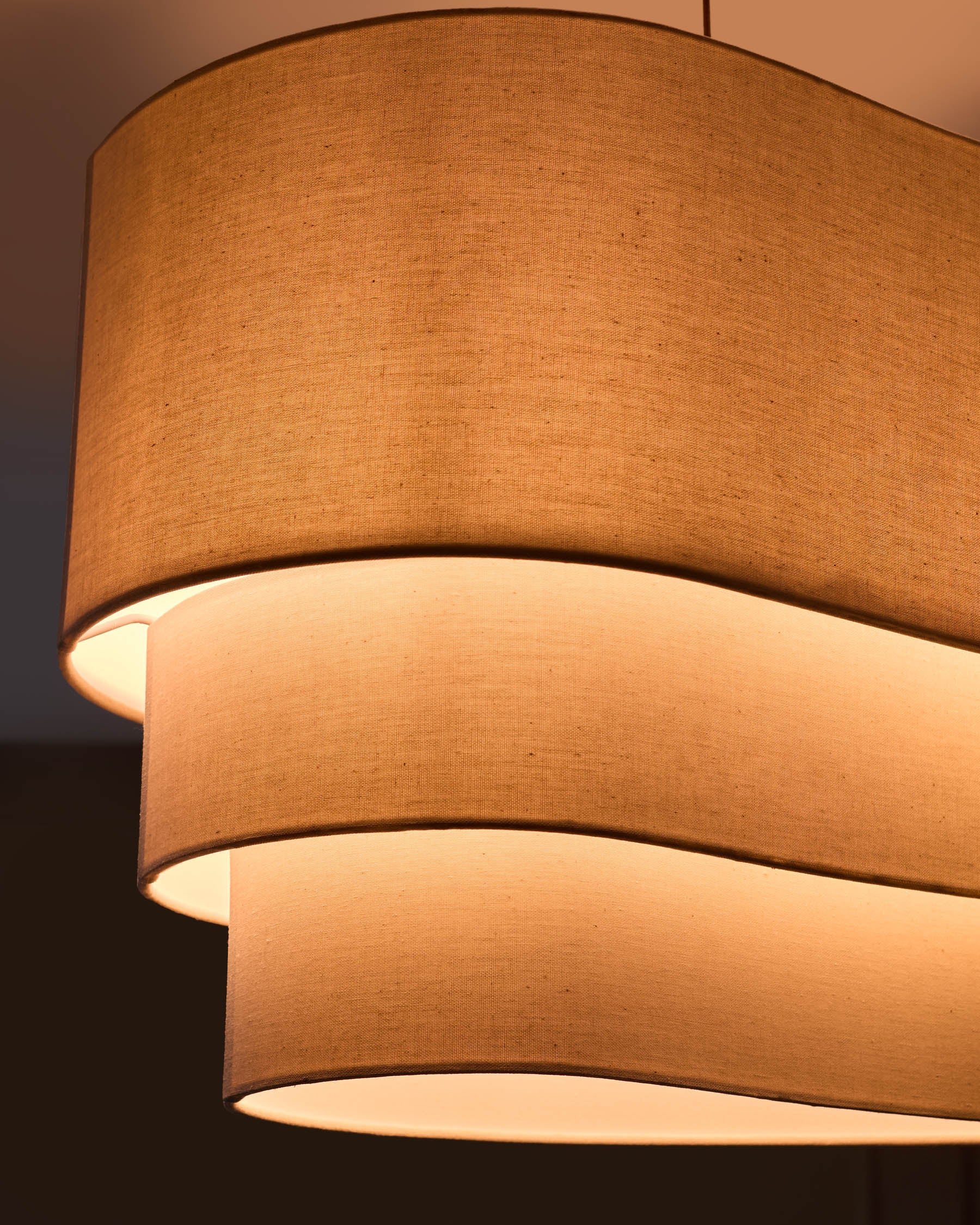 Burleigh 2-bulb pendant light with stacked natural linen shades, warm glow from interior illumination visible.