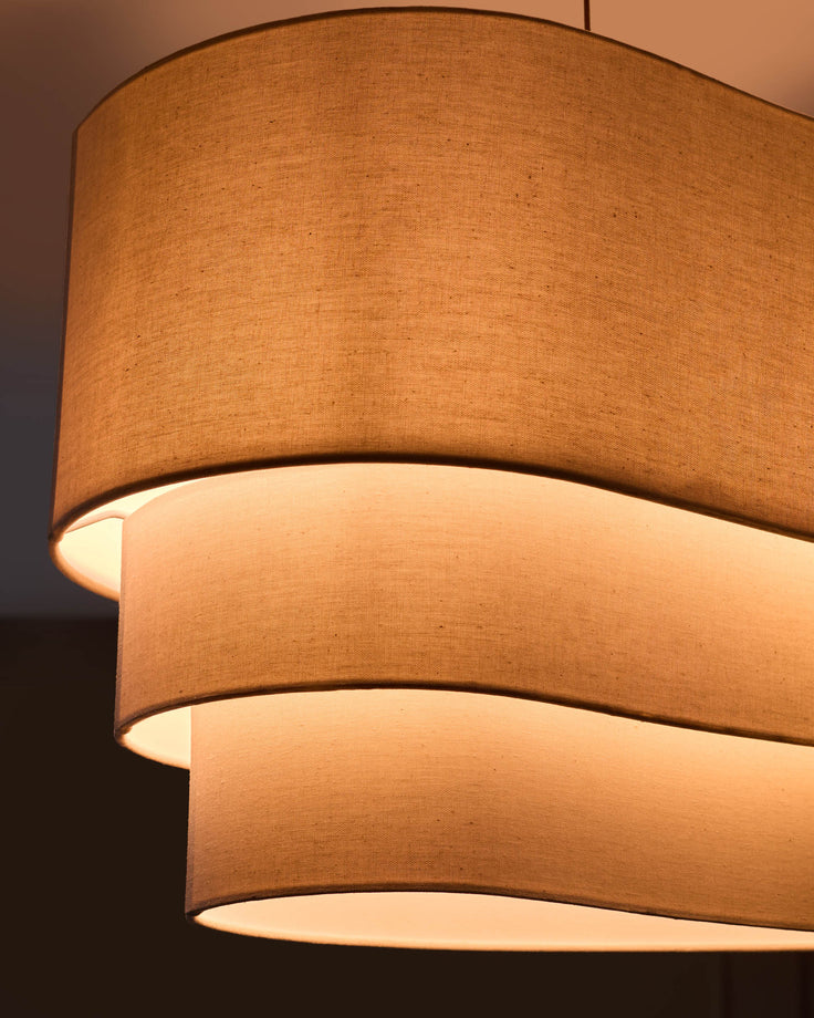 Burleigh 2-bulb pendant light with stacked natural linen shades, warm glow from interior illumination visible.