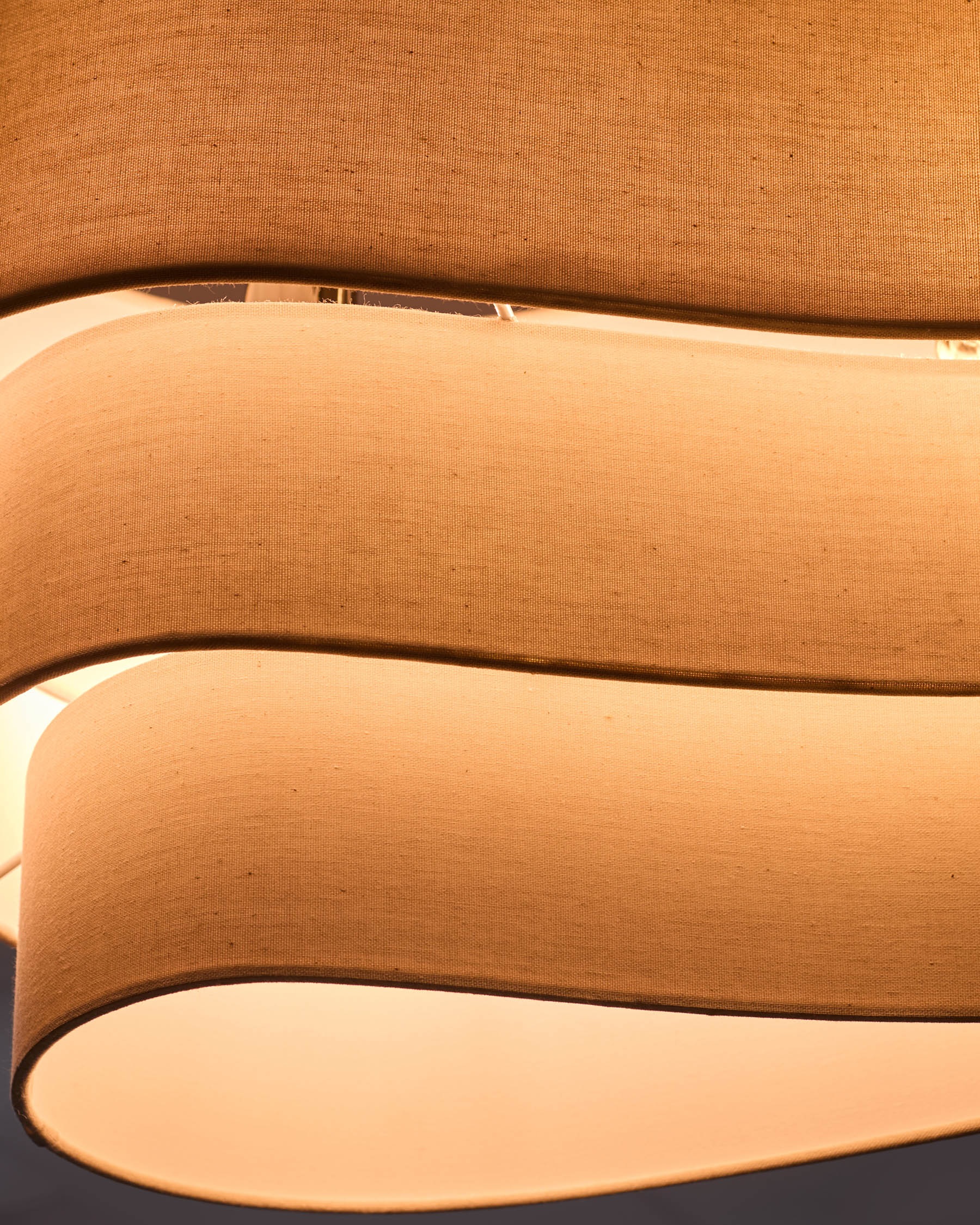 Natural linen shades stacked showing curved cylindrical design and warm cream finish.
