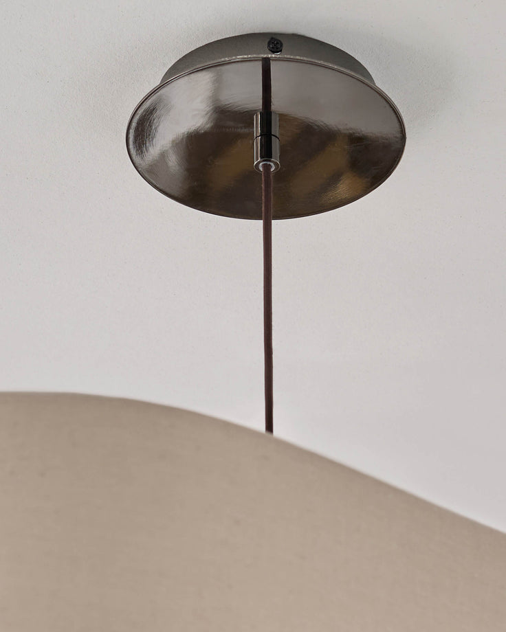 Brushed nickel ceiling canopy with dark rod suspending a natural linen drum shade pendant light.
