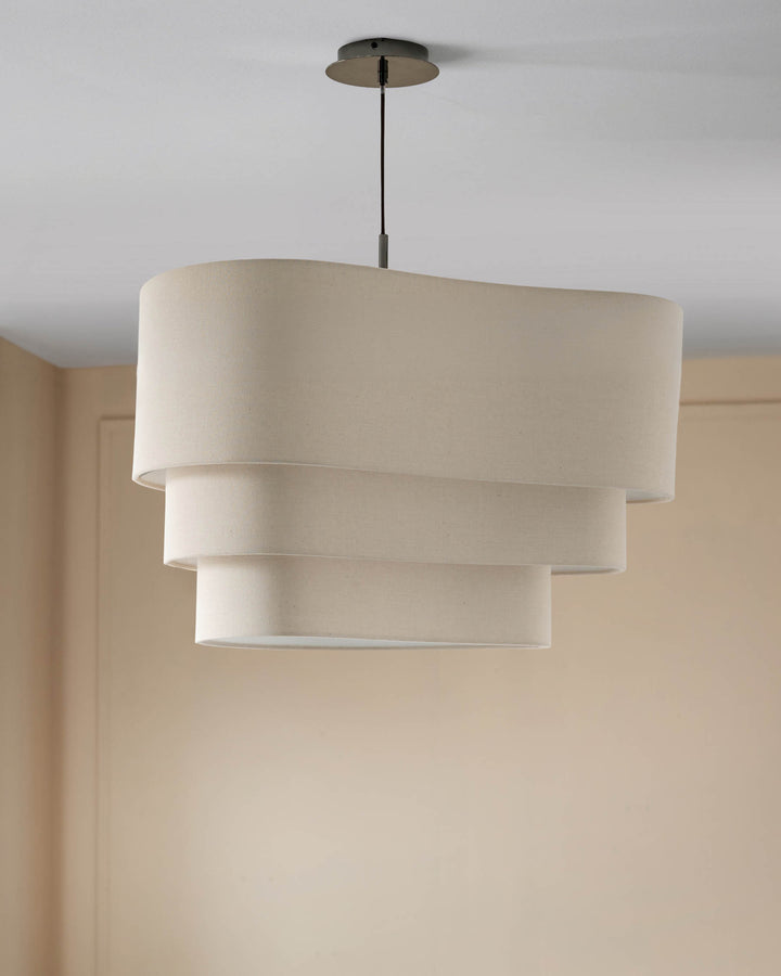 Burleigh 2-bulb pendant light in natural linen with stacked cylindrical shades and bronze hardware, hanging in cream interior.