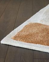 Close-up of a patterned shag rug in cream and brown on a dark wooden floor. Ideal for adding texture and warmth to any room.
