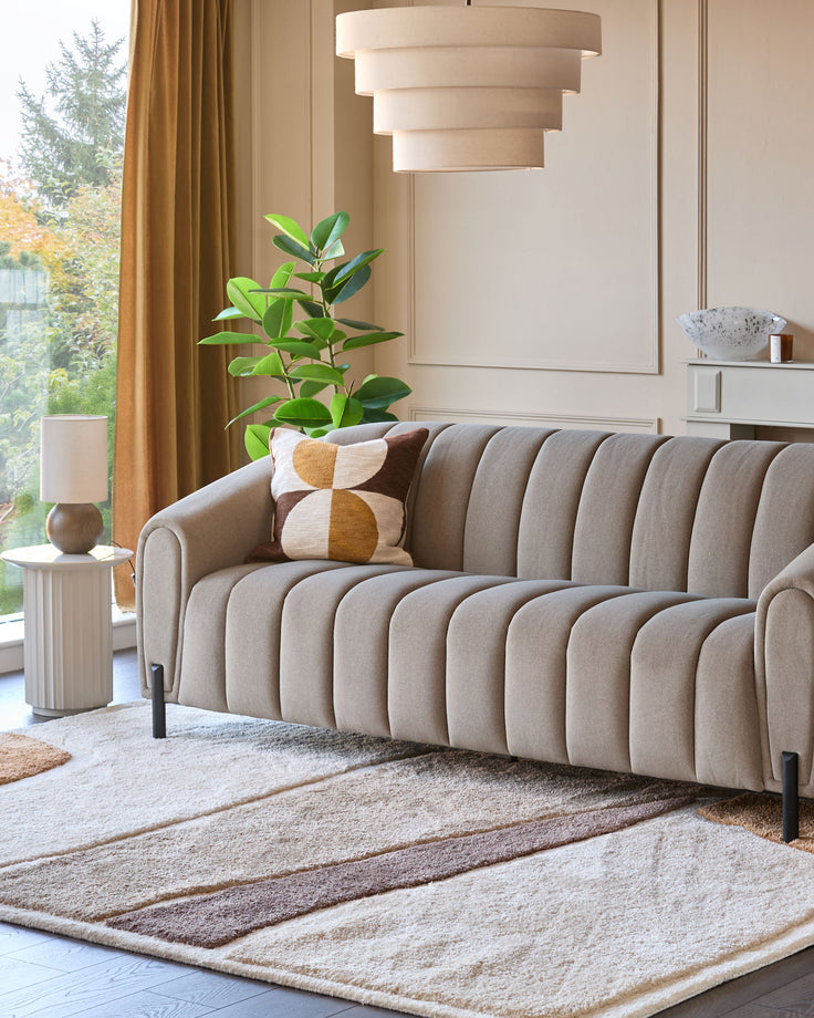 Stylish living room featuring a fluted sofa, geometric rug, and modern lamp. Light and airy, showcasing comfort and design.