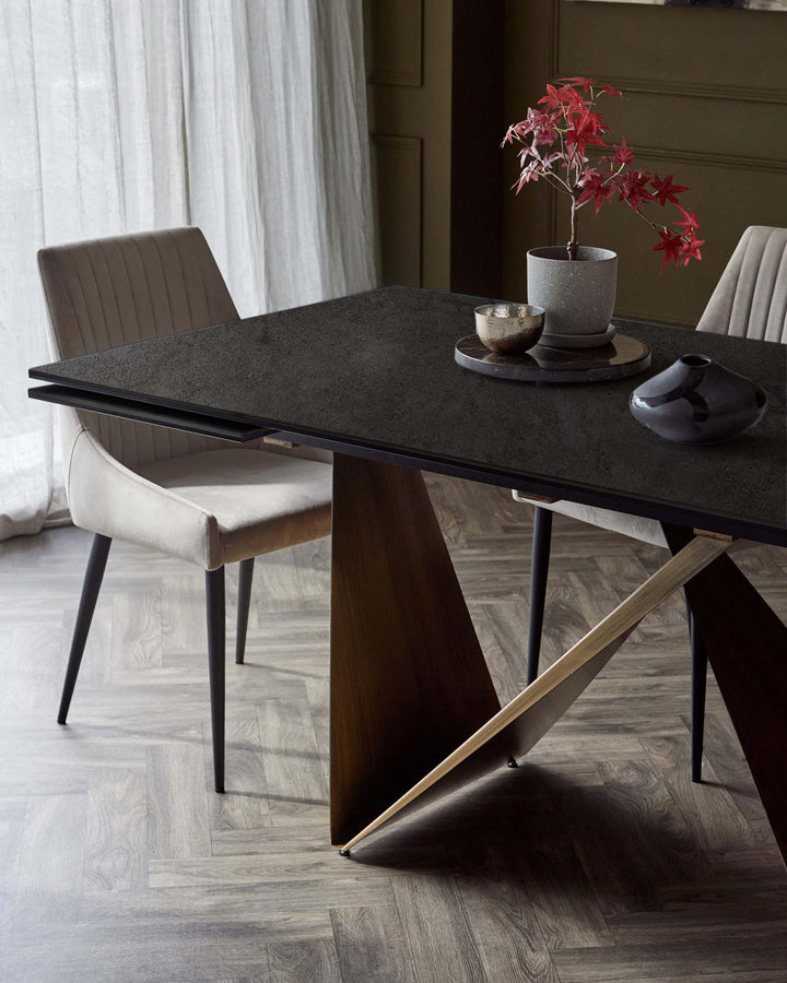 Elegant black dining table with geometric wooden base, complemented by stylish beige chairs and decorative plant accents.