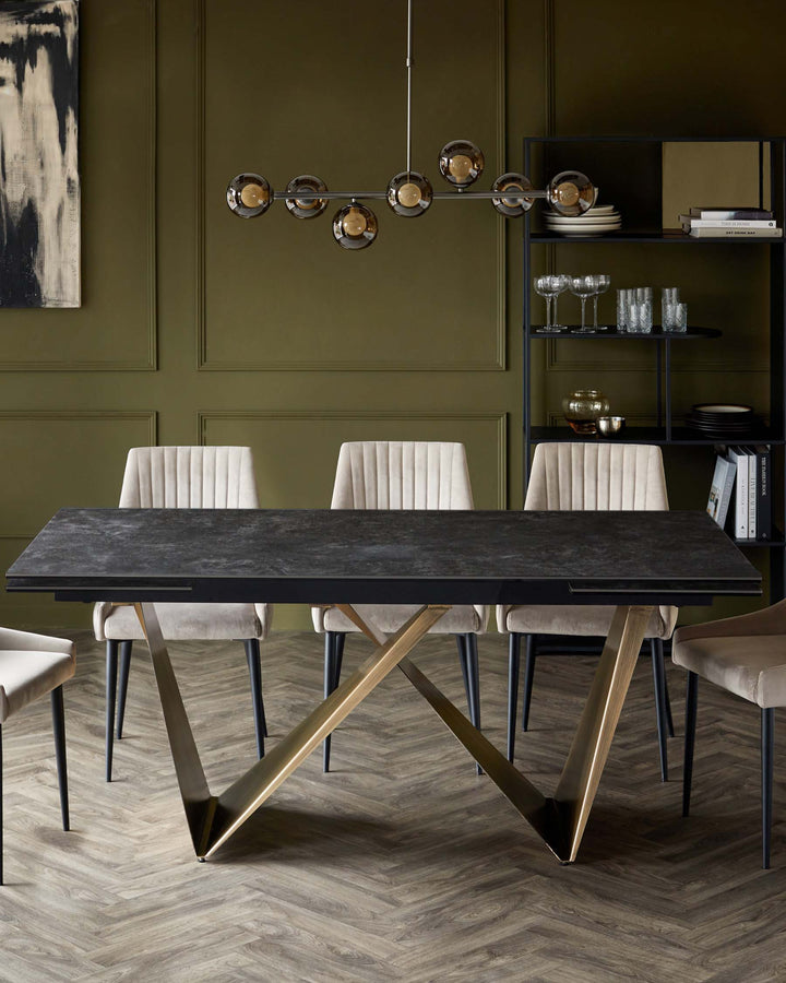 Elegant dining table with a dark top and gold V-shaped base, paired with textured beige chairs, under a modern pendant light.
