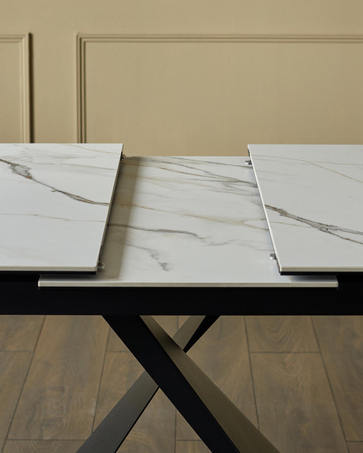 An extendable dining table with a faux marble top and black, criss-cross legs.