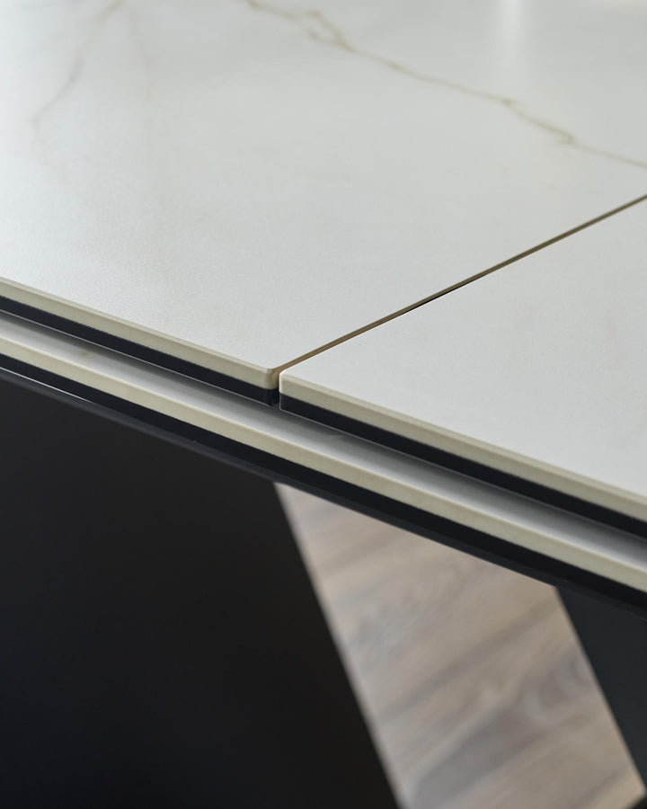 Close-up of a stylish table featuring a light stone top, with a modern black frame and wooden accents.