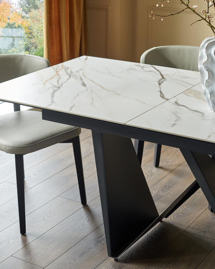 A contemporary dining set featuring a marble-topped table with sleek, dark metal legs and matching upholstered chairs.