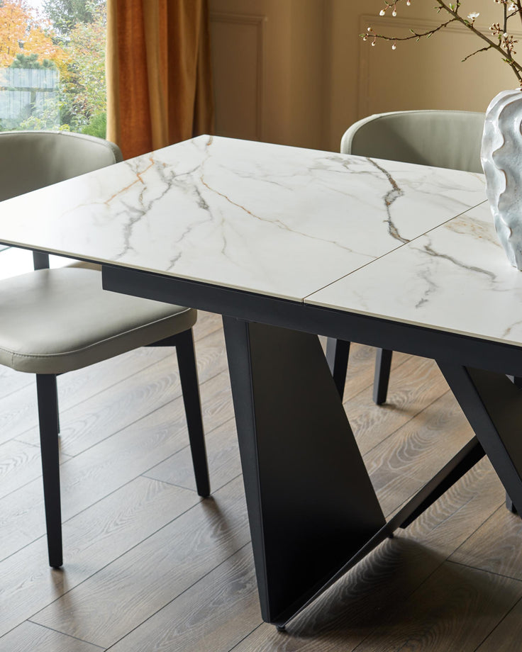A contemporary dining set featuring a marble-topped table with sleek, dark metal legs and matching upholstered chairs.