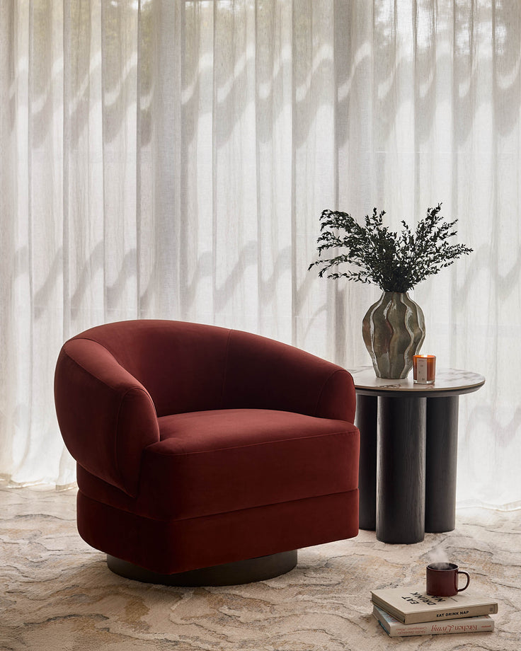 Callan accent chair in toffee red velvet with curved barrel shape, shown in styled living room setting.