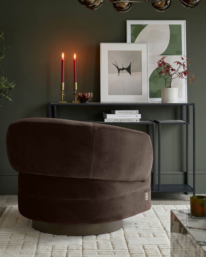 A plush brown swivel chair sits on a textured rug, complemented by a sleek console table with art prints and candles.