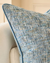 Large blue textured cushion with woven fabric detail, displayed on a cream upholstered chair arm.