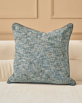 Callie cushion in large blue, featuring a textured woven fabric with blue and neutral tones, displayed on a cream sofa.