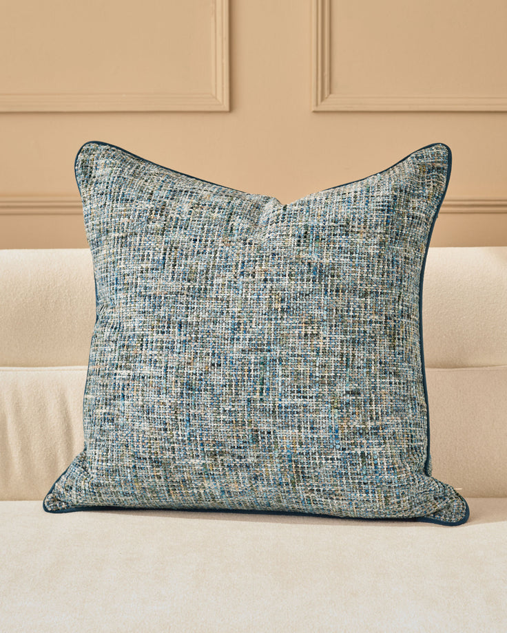 Callie cushion in large blue, featuring a textured woven fabric with blue and neutral tones, displayed on a cream sofa.