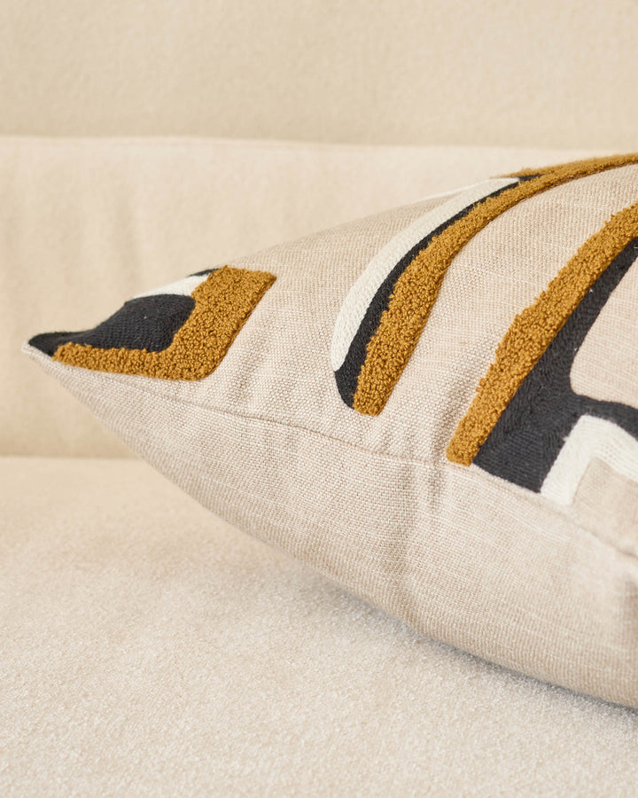 Camille medium cushion in natural linen with mustard and charcoal geometric stripe pattern, angled side view.