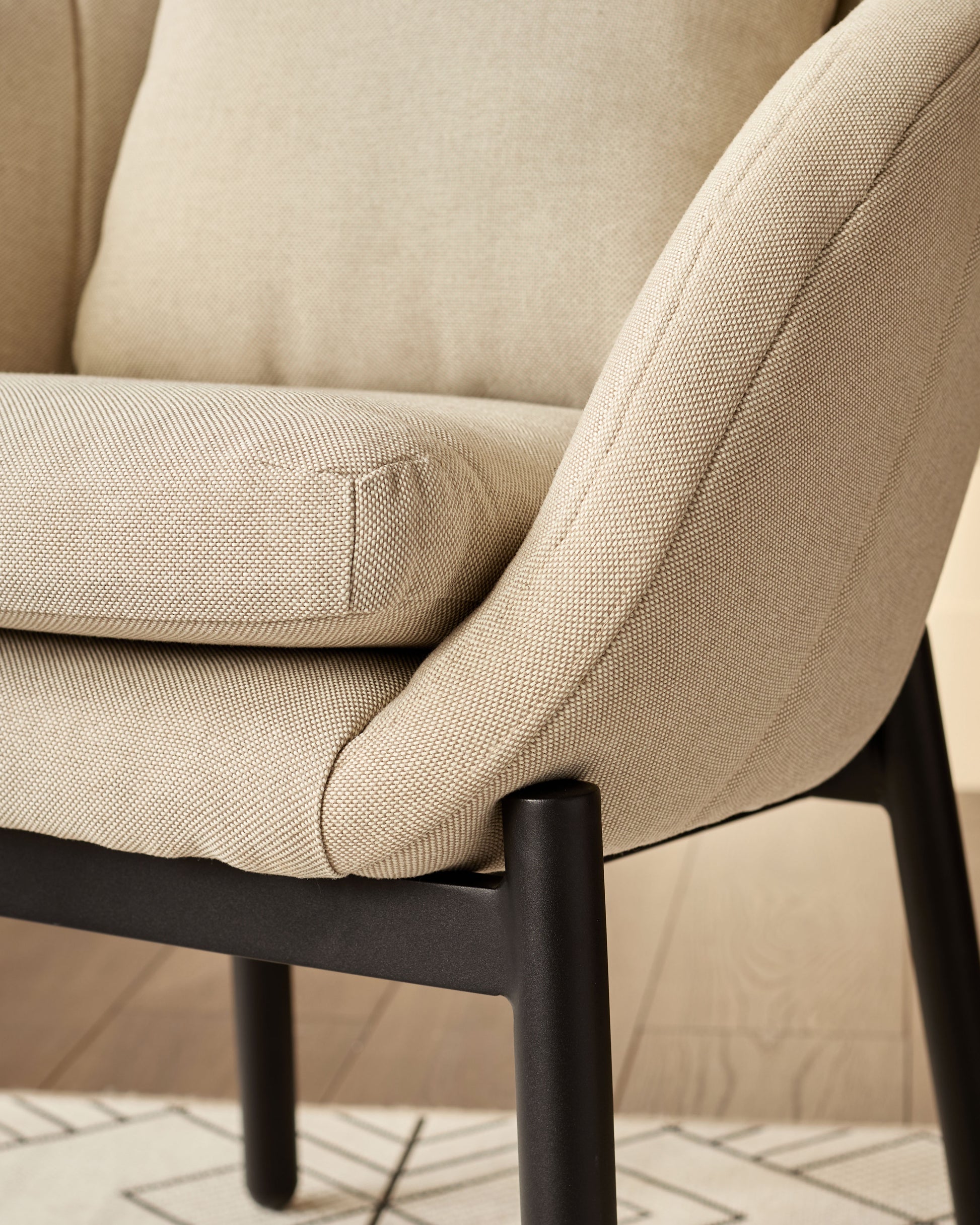 Camilo dining chair with beige fabric seat and backrest, black wooden legs, close-up detail view.