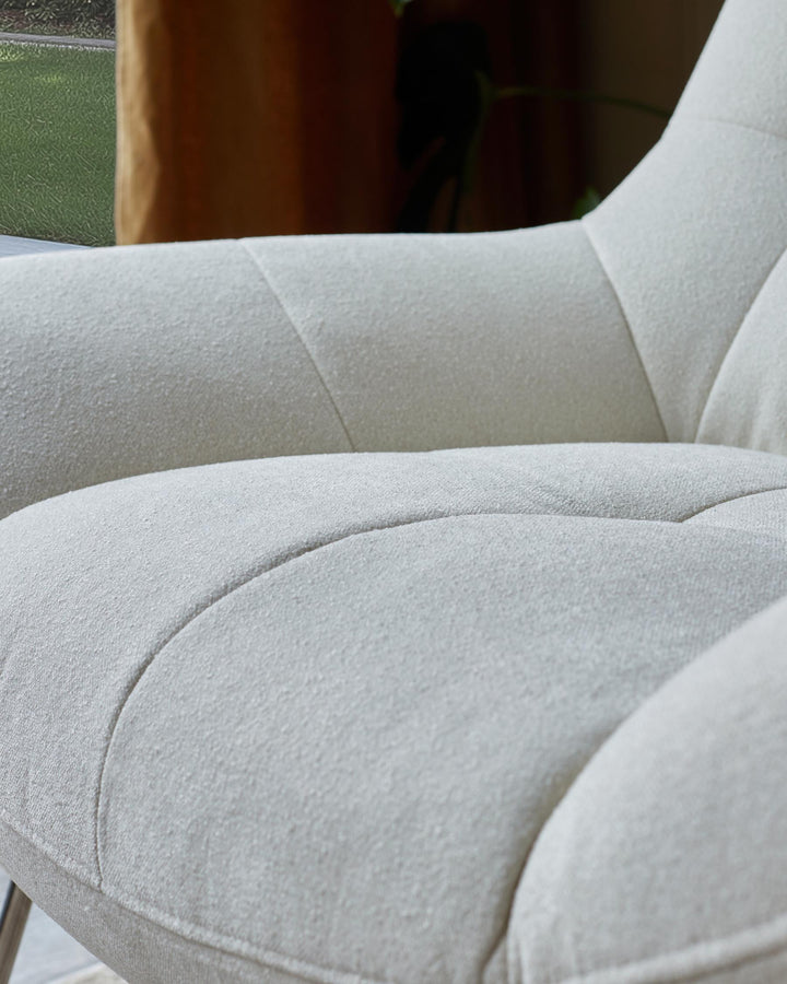 Close-up of a cream, upholstered chair with a quilted design. Comfortable and stylish seating.