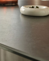 Close-up of dark grey ceramic dining table surface with white bowl and utensils.