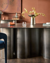 Carlo 8-seater dining table in dark grey ceramic with brushed metal base, styled with flowers and tableware.