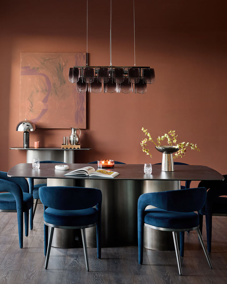 Dark navy velvet dining chair with curved back and metal legs, shown in modern dining room setting.