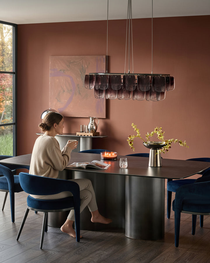 Rhett dining chair in dark navy velvet, shown at dining table in modern terracotta room setting.