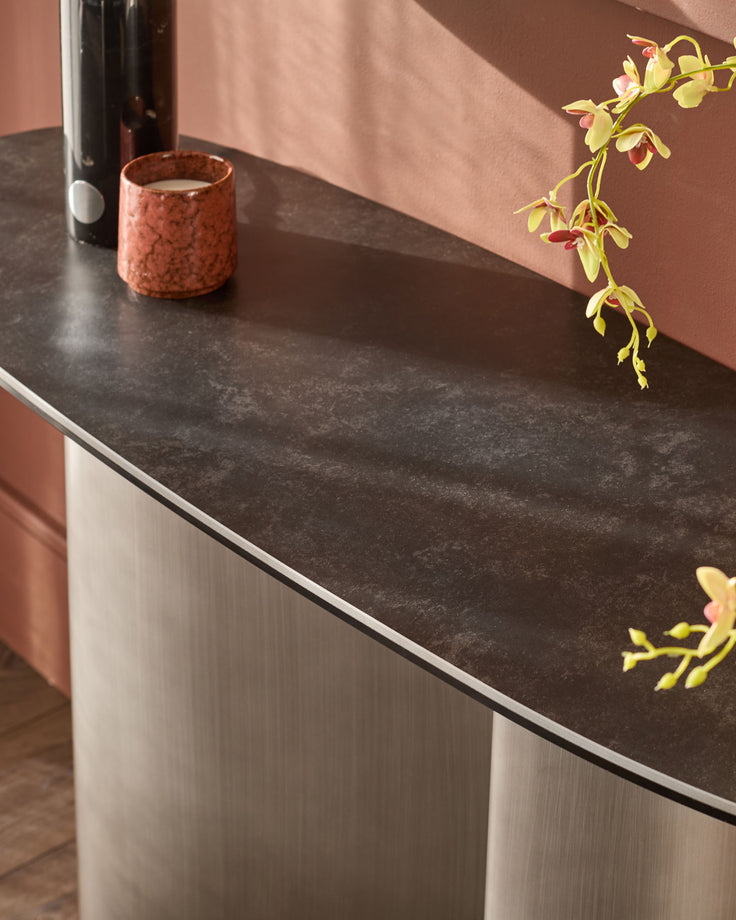 Carlo console table in dark grey ceramic with white ribbed base, styled with decorative candle and orchid flowers.