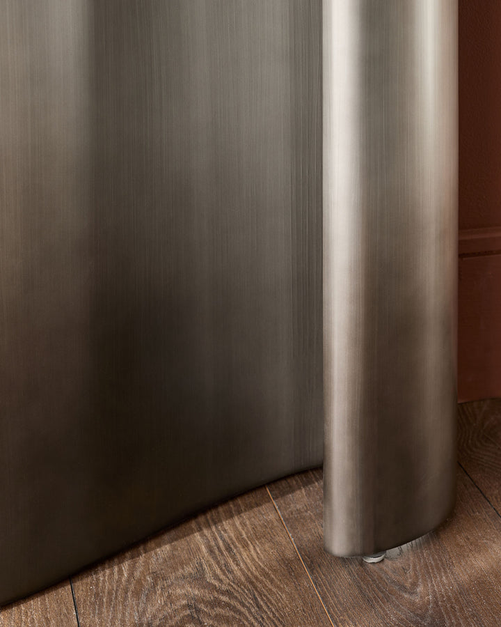 Carlo console table in dark grey ceramic with brushed metal cylindrical support leg on wood flooring.