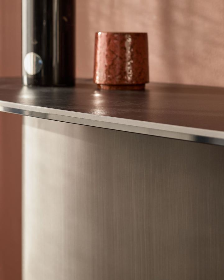 Carlo console table in dark grey ceramic with stainless steel trim, featuring a polished top surface and textured base.