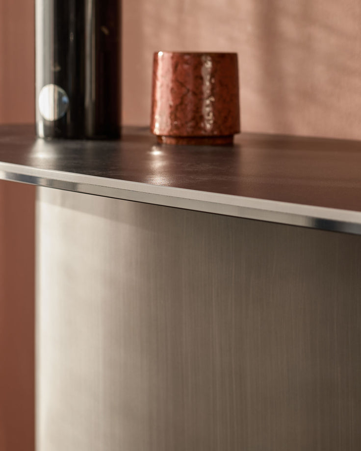 Carlo console table in dark grey ceramic with stainless steel trim, featuring a polished top surface and textured base.