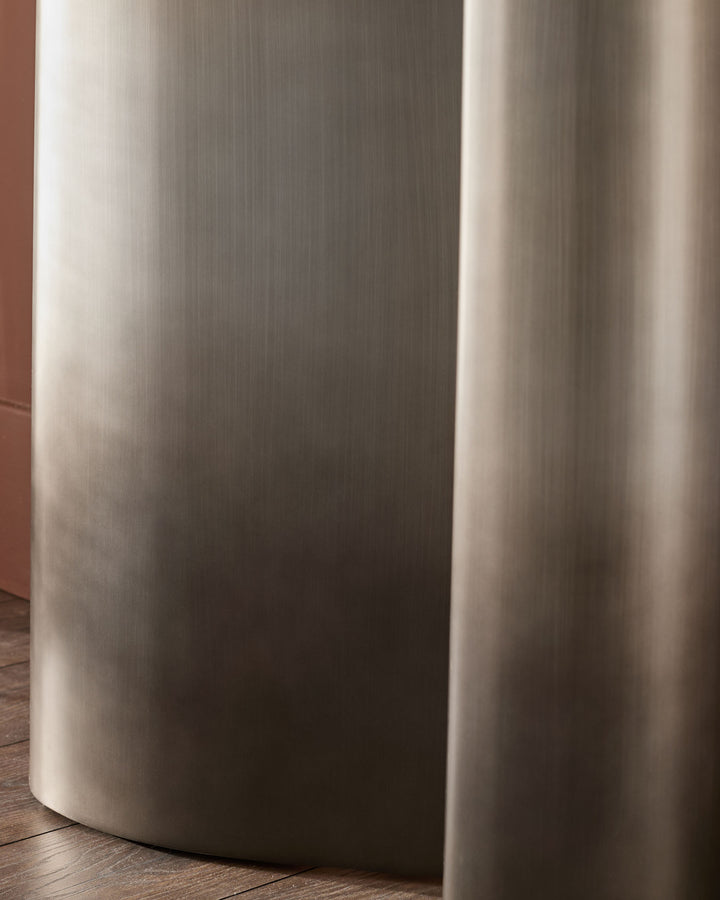 Carlo console table in dark grey ceramic, cylindrical base detail, close-up side view on wooden floor.