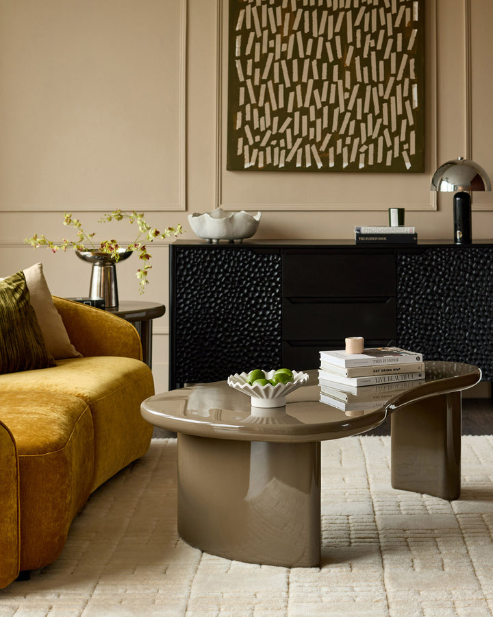 Carmela coffee table in gloss olive green with curved organic shape, displayed in a modern living room setting.
