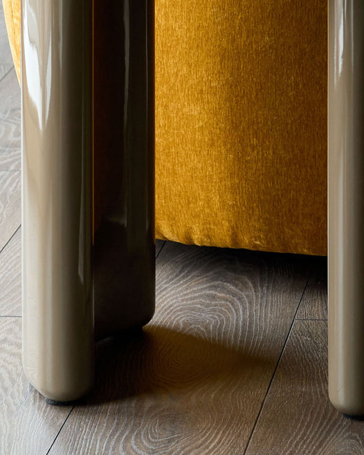 Carmela side table in gloss olive green, shown from front angle on wooden flooring with door slightly ajar.