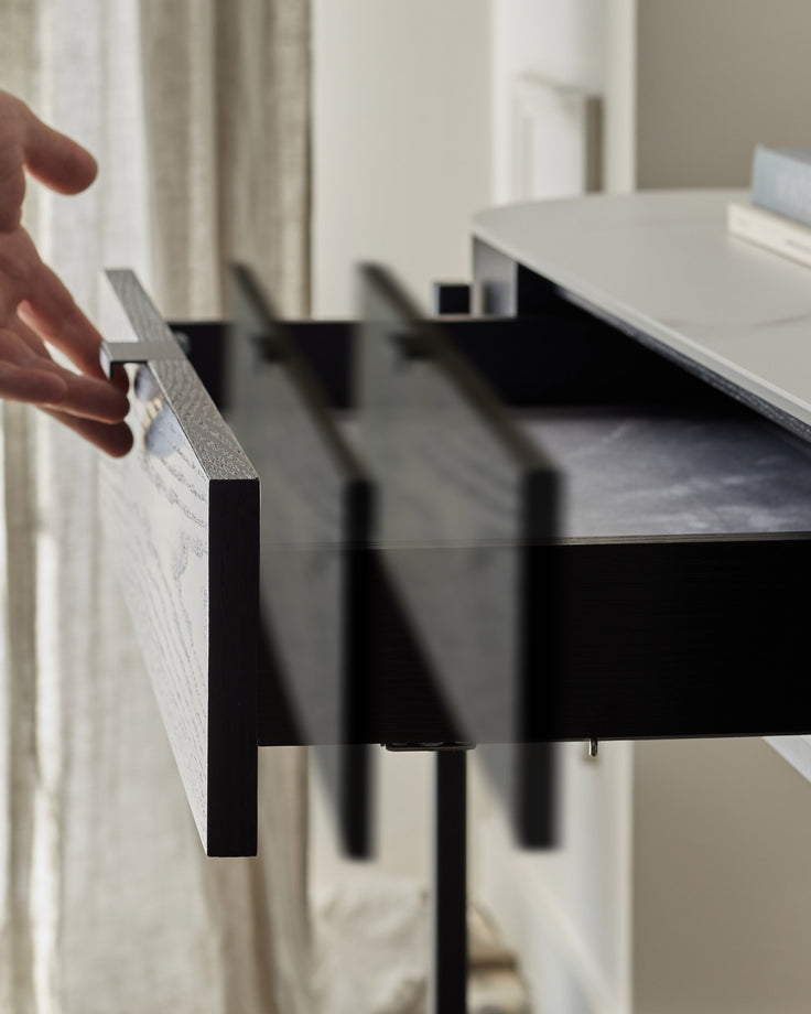 Black console dressing table with textured wood handle detail, showing sleek modern design in minimalist interior setting.