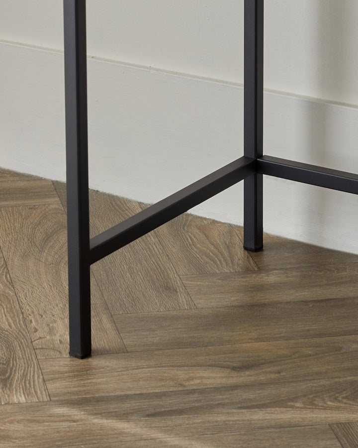 Carmen console dressing table with black metal frame on wooden floor, side angle view.