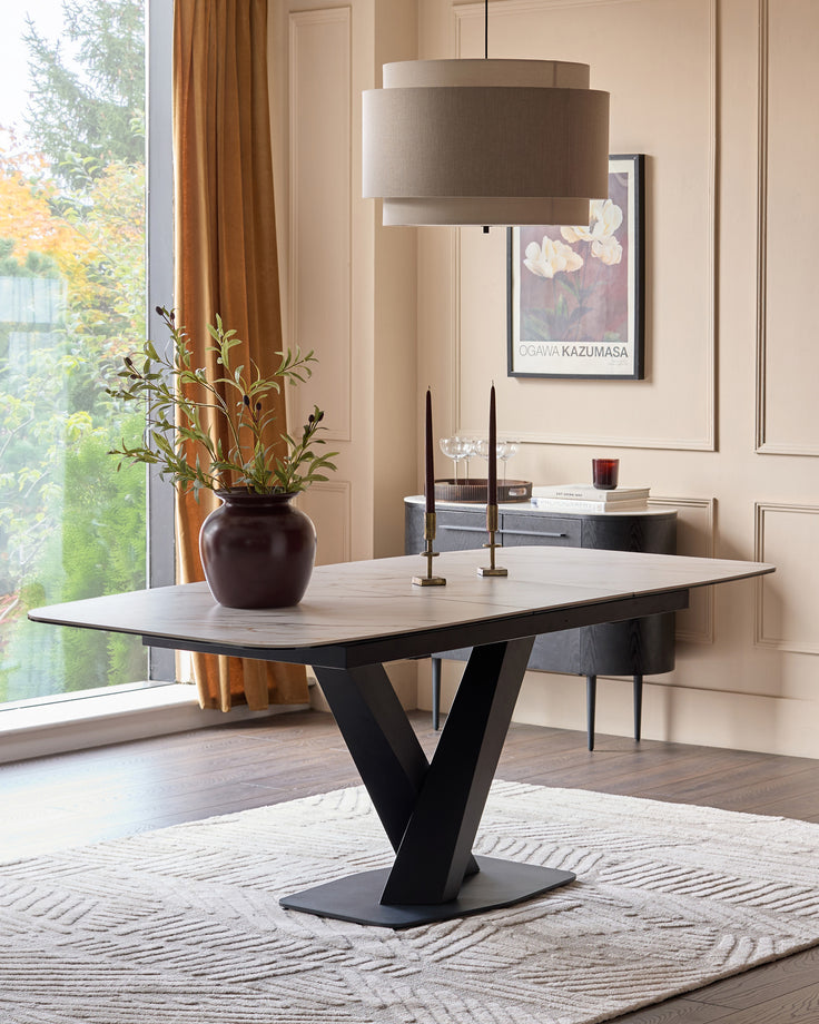 Carter extending dining table with light ceramic top and black V-shaped pedestal base in modern dining room setting.