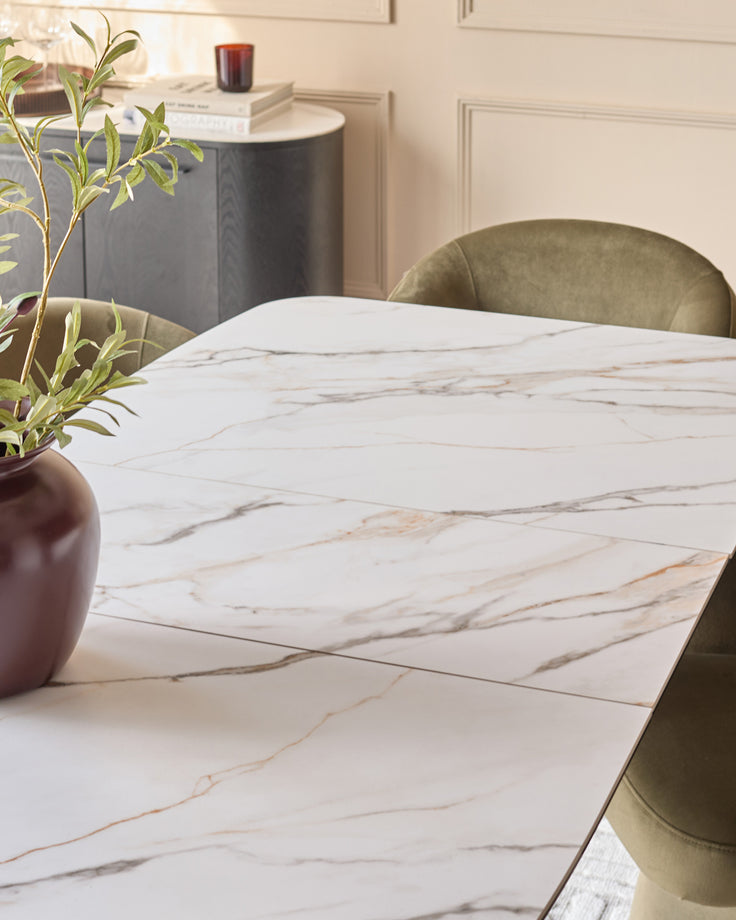 Carter extending dining table in white marble ceramic with green upholstered chairs in modern dining room.