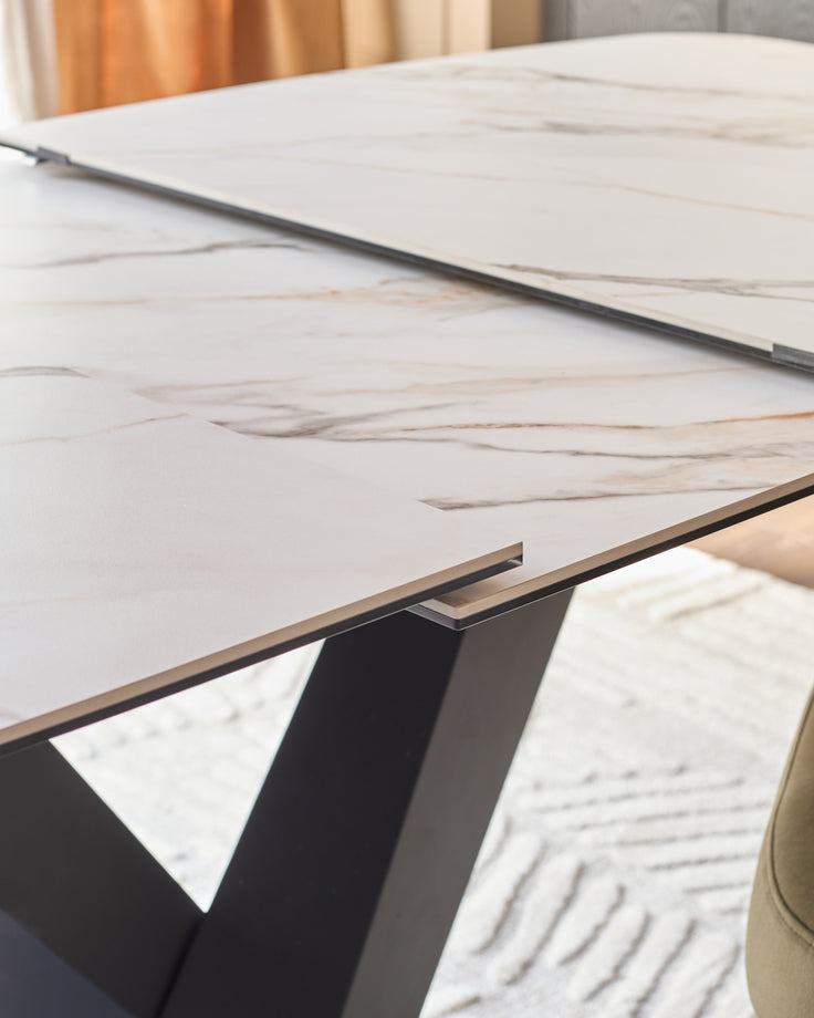 Carter extending dining table with ceramic top in natural finish, showing black metal base and extension mechanism detail.