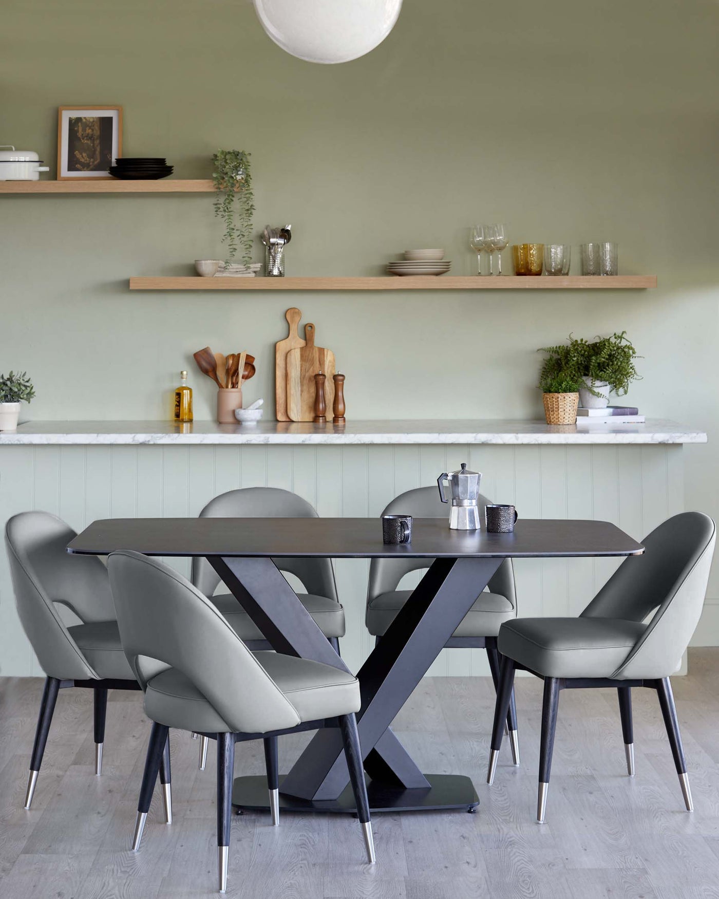 Modern dining furniture with a rectangular black table featuring a unique X-shaped base. Surrounding the table are six sleek, grey upholstered chairs with black legs tipped with metallic accents. The clean lines and contemporary design create an elegant and sophisticated dining set-up.