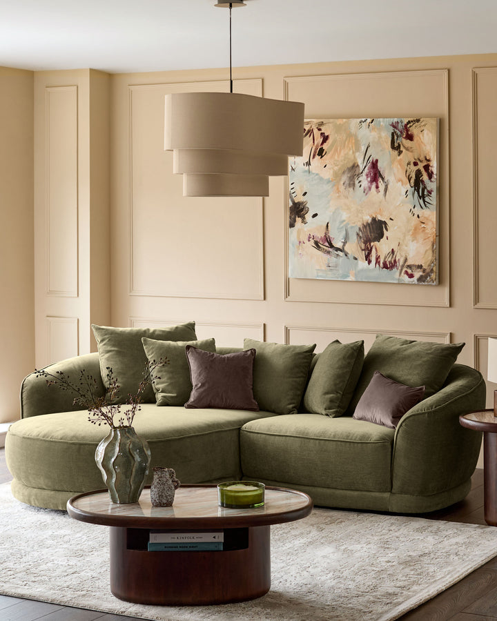 Olive green left-hand corner chaise sofa with curved arms and plush cushioning in a styled living room setting.