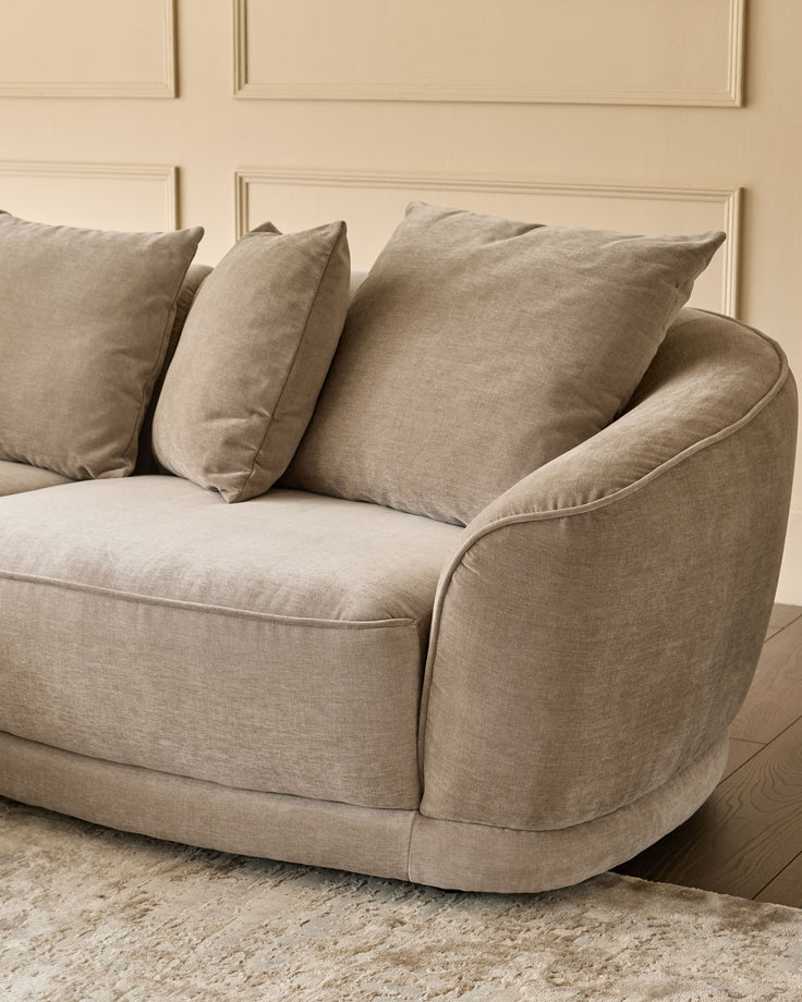 Caspian left-hand corner chaise sofa in mink fabric, shown from side angle with decorative pillows and curved armrest detail.
