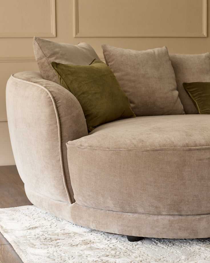 Caspian left-hand corner chaise sofa in mink fabric with green accent pillows, curved design, angled side view.