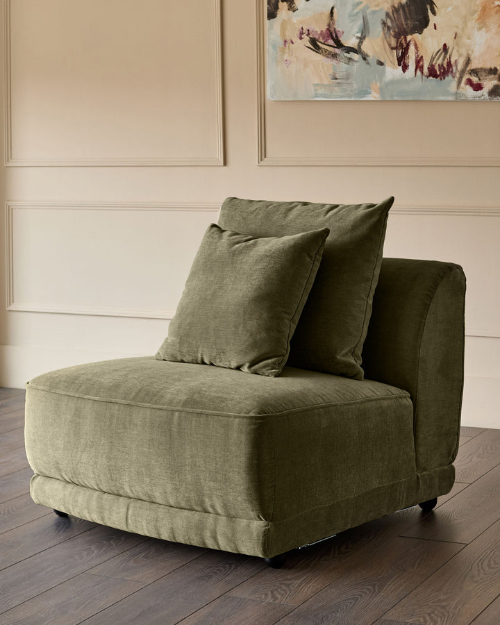 Caspian single module fabric chair in olive green with decorative pillows, angled side view on dark wood floor.