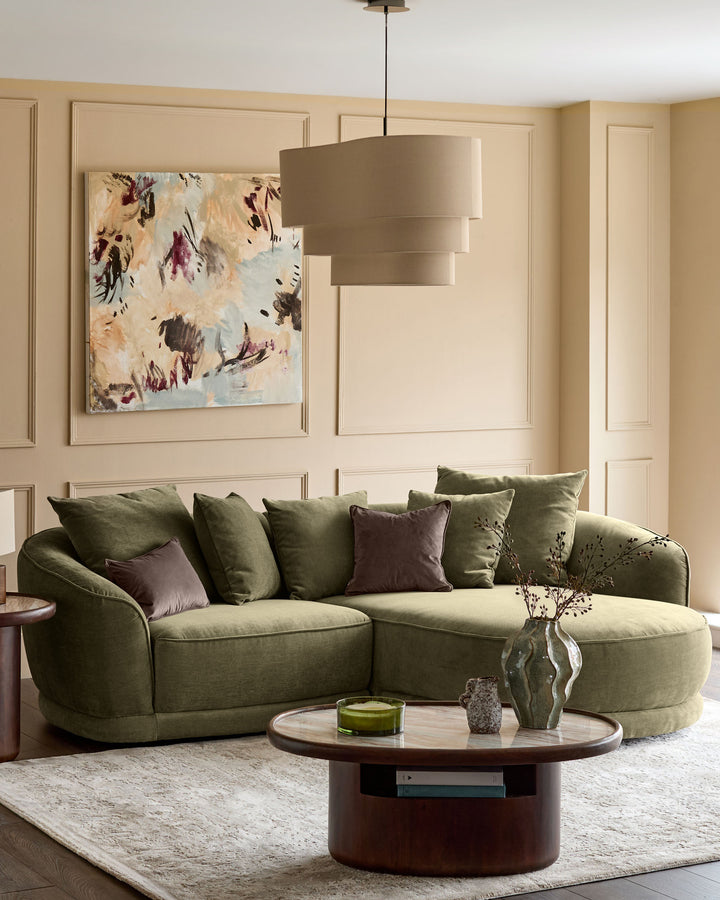 Olive green corner chaise sofa with curved arms and plush cushions, styled in a contemporary living room setting.