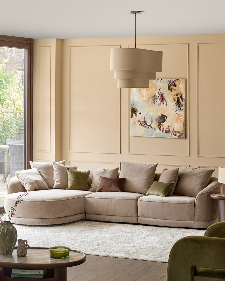 Caspian single module fabric sofa in mink, curved design, displayed in cream living room setting with coordinating pillows.