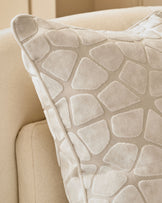 Cassidy medium ivory cushion with textured quilted pattern, displayed on a cream upholstered chair.